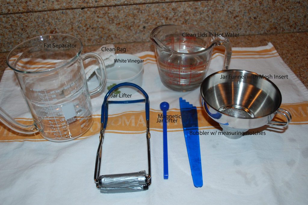 Overhead view of tools and equipment necessary to can and preserve food laid out on a table