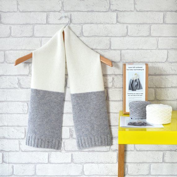 A grey brick wall with a white and gray scarf on a hanger.