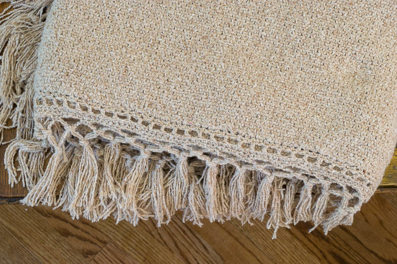 Closeup of knit blanket (with crochet fringe) pattern using linen stitch.