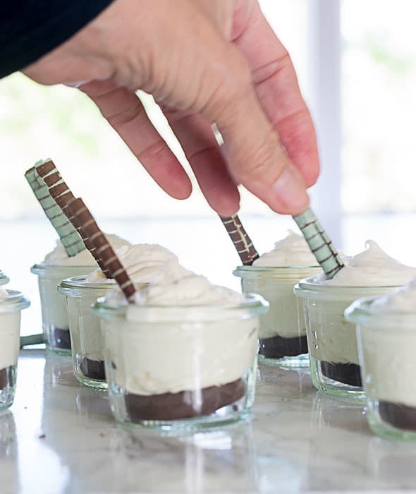 Putting Chocolate Straws into Mini White Chocolate Mint Mousse cups