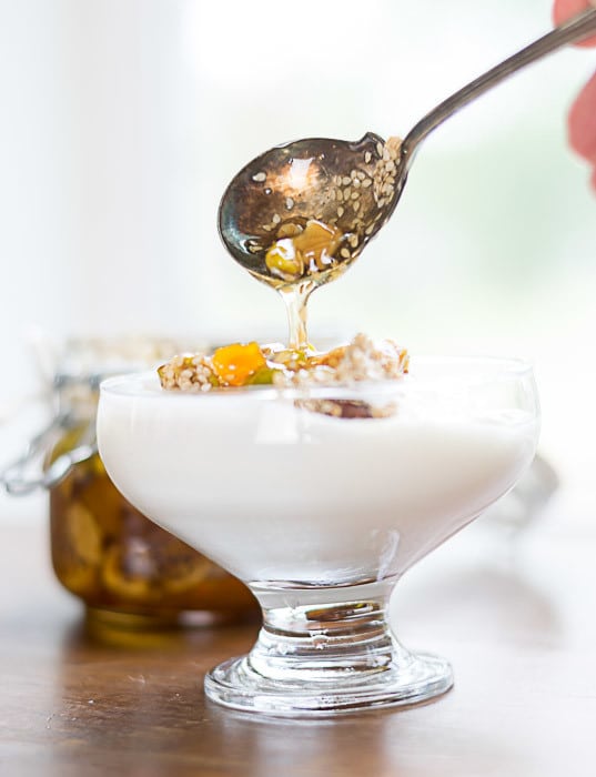 drizzling fruits and nuts in honey over yogurt